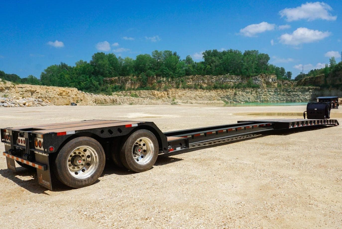 Lowboy trailer with a worn wood deck at a job site